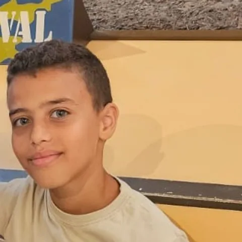 صبي يبتسم أمام جدار أصفر